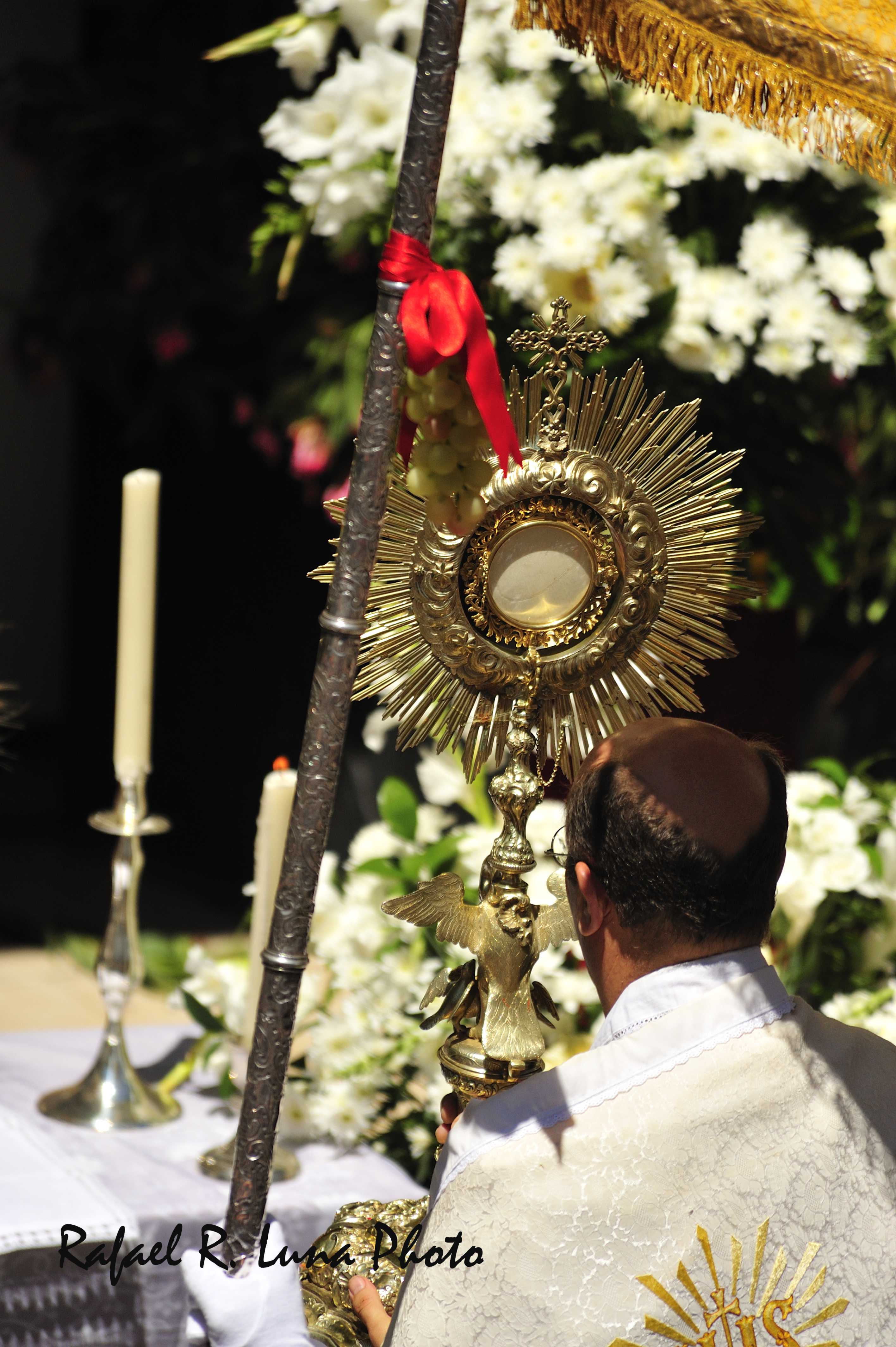 Fotograf&iacute;a donde observamos como el p&aacute;rroco, porta el Sant&iacute;simo bajo el pal&iacute;o que es transportado por los fieles.