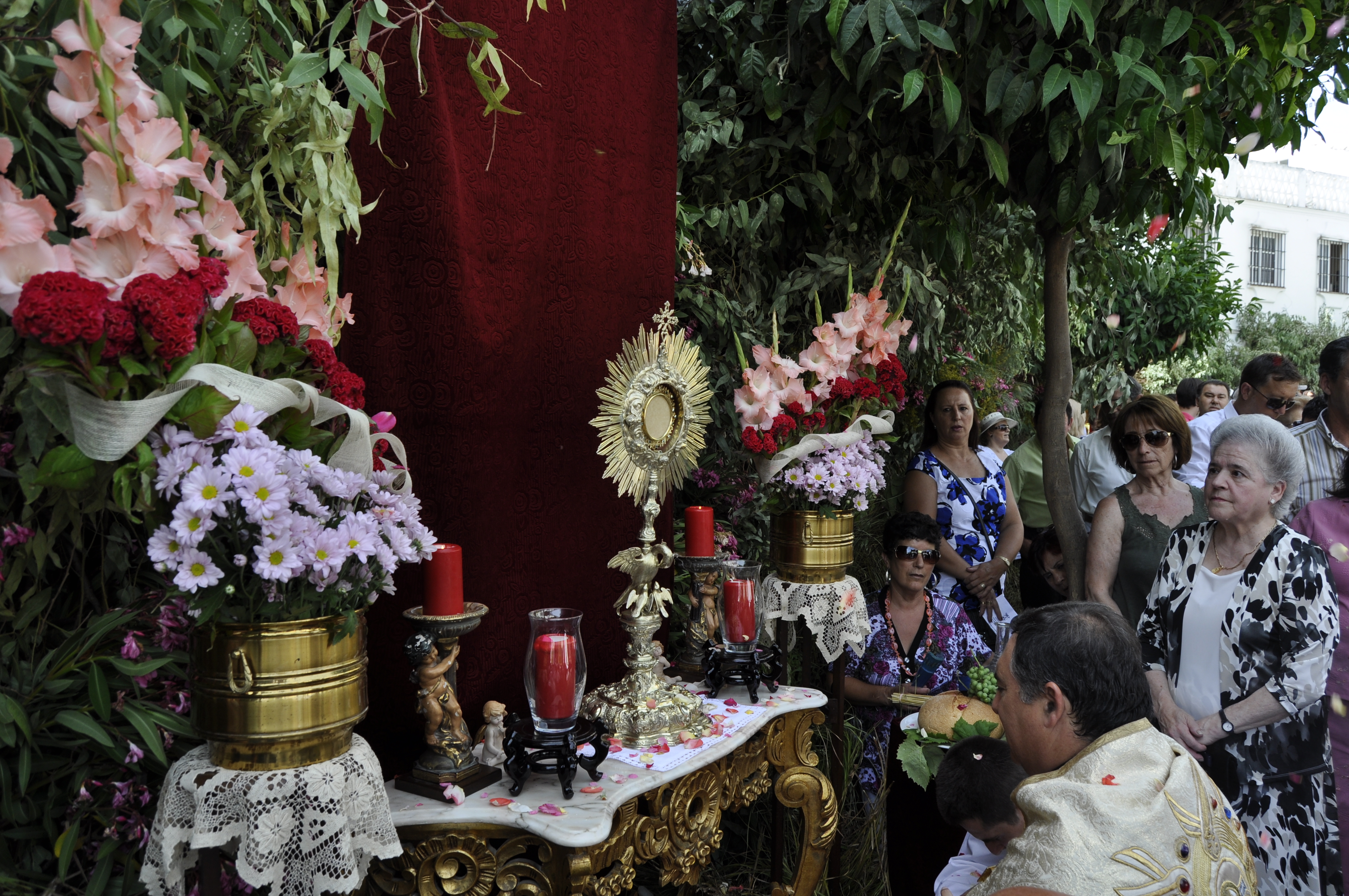 Fotograf&iacute;a donde vemos al p&aacute;rroco orando en un altar de los que est&aacute;n situados por las calles de la villa.